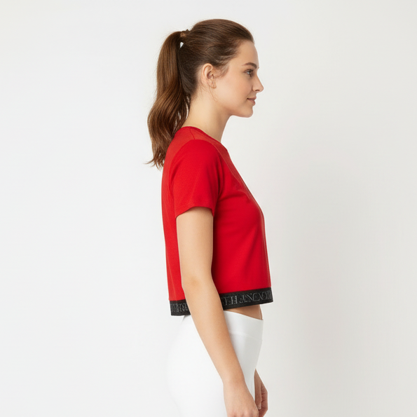 Woman wearing a red crop top and white pants on a white background